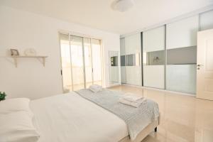 a white bedroom with a large bed and large mirrors at אריה במדבר - וילה מושלמת עם בריכה פרטית מחוממת באילת in Eilat