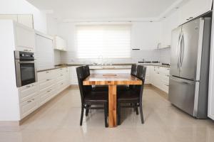 a kitchen with a wooden table and a refrigerator at אריה במדבר - וילה מושלמת עם בריכה פרטית מחוממת באילת in Eilat
