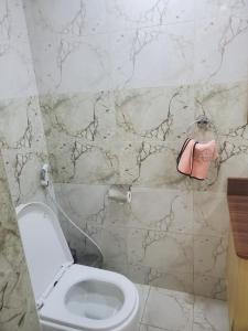ein Badezimmer mit Toilette und einer rosa Handtasche an der Wand in der Unterkunft Noah's Ark in Kampala + 3 Fotos