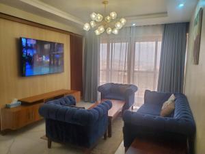 ein Wohnzimmer mit 2 blauen Stühlen und einem TV in der Unterkunft Noah's Ark in Kampala