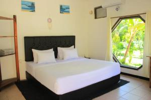 a bedroom with a large white bed with a window at Malaka ocean homestay in Kuta Lombok