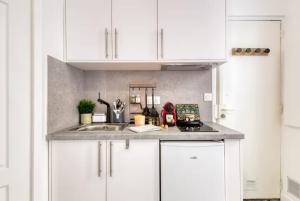 a kitchen counter with white cabinets and a sink at Le Petit nid cocooning - Studio chaleureux et élégant in Aubervilliers +7 photos