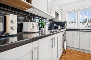 une cuisine avec des armoires blanches et un évier dans l'établissement Windrush Court, The Spacious & Comfy 3BR House By AltoLuxo Short Lets & Serviced Accommodation With Free WiFi & Parking, à Thornbury 22 autres photos