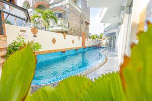 ein Schwimmbad in einem Gebäude mit Grünpflanzen in der Unterkunft Cham Charm Apartment Hotel Mui Ne in Mui Ne
