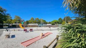 a park with a playground with a slide and chairs at Mobil-home 565 tout confort camping SIBLU 4 étoiles in Gastes