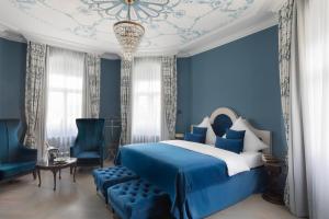 a blue bedroom with a bed and a chandelier at Schloßhotel Althörnitz Neubau in Hörnitz