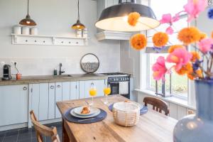 a kitchen with a wooden table with two glasses of orange juice at Karakteristieke boerderij met wellness in Friesland in Suameer