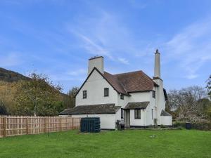 an old white house with a fence in a yard at Bossington Green Cottage in Porlock