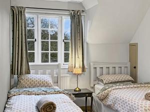 two beds in a bedroom with a window at Bossington Green Cottage in Porlock