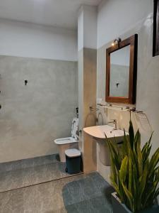 Un baño con lavabo, inodoro y espejo. en Baba Place Thalpe, en Galle