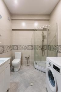 a bathroom with a shower and a toilet and a washing machine at The Urban Retreat in Tbilisi City