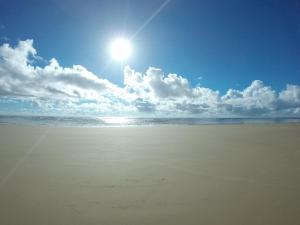 a beach with the sun in the sky and the ocean at Guest House Boki da Zezé in Marau