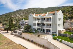 une grande maison blanche avec une colline en arrière-plan dans l'établissement Nostos - Psili Ammos Appartments, à Psili Ammos