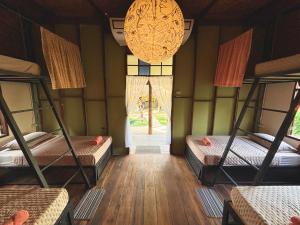 Habitación con 3 literas y lámpara de araña. en Sanctuary Hostel - Art & Adventure, en Phra Ae beach