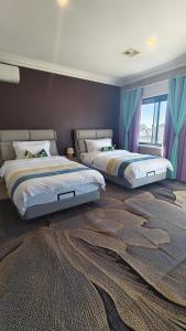 two beds in a bedroom with blue curtains at Sunny Ocean View Retreat in Perth