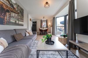 ein Wohnzimmer mit Sofa und Fernseher in der Unterkunft Newly Refreshed Family-stay For 7 By The Lake in Ewijk
