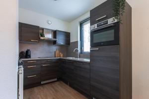 eine Küche mit dunklen Holzschränken und einer Mikrowelle in der Unterkunft Newly Refreshed Family-stay For 7 By The Lake in Ewijk + 77 Fotos