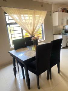 a dining room table with black chairs and a window at Executive house in Lusaka