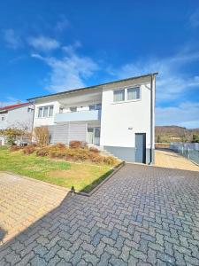 un edificio blanco con una entrada delante de él en Basilisk Homes - in Grenzach-Wyhlen bei Basel - 4 x Moderne Fewos je 1bis2, 1bis4 oder 1bis6 Pers mit Küche und Balkon oder Terrasse - Parkplätze vorhanden, en Grenzach-Wyhlen