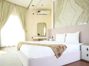 Un dormitorio con una gran cama blanca y un espejo. en Dana Beach Resort, en Al Sharqiyah 41 fotos más