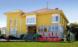 ein gelbes Haus mit roten Stühlen davor in der Unterkunft Hotel Restaurante el Fornon in Novellana