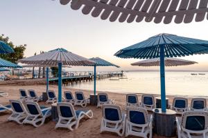 a group of chairs and umbrellas on a beach at MinaMark Beach Resort for Families and Couples Only in Hurghada