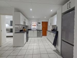 Gulls Nest في هيرمانوس: مطبخ كبير مع خزائن بيضاء وأرضية من البلاط