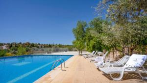 a row of white lounge chairs next to a swimming pool at Cortijo El Álamo 1 Vélez Blanco by Ruralidays in Vélez Blanco