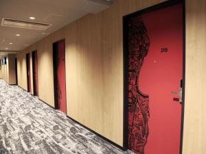 Una fila de puertas en un pasillo con paredes rojas. en ibis Osaka Umeda, en Osaka 58 fotos más