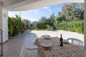 een tafel met een fles wijn op een patio bij Apt Grecale e Ponente vista mare - Salento Reservation in Isola della Malva