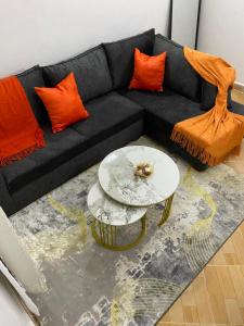 Taste of Home by Chel في ناكورو: أريكة سوداء مع وسائد برتقالية وطاولة