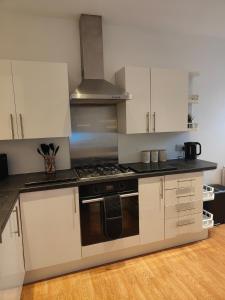 eine Küche mit weißen Schränken und einem Herd mit Backofen in der Unterkunft luxury Maisonette near beach in Morecambe