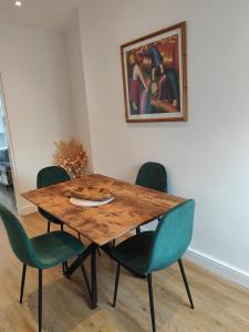 einem Esstisch mit grünen Stühlen und einem Gemälde in der Unterkunft luxury Maisonette near beach in Morecambe + 2 Fotos
