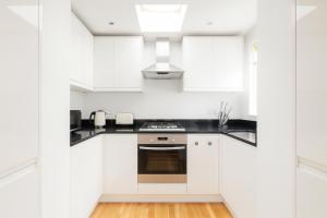 a white kitchen with black countertops and white cabinets at Superb 2 Bed Apartment in Battersea in London
