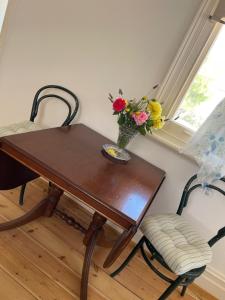 a wooden table with a vase of flowers and a chair at The Gilded Hare in Moonta in Moonta