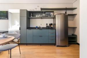 eine Küche mit einem Kühlschrank aus Edelstahl und einem Tisch in der Unterkunft Edificio Village Lofts - Ao lado da Vila Germânica in Blumenau