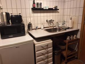 a small kitchen with a sink and a microwave at Lille bolig med egen indgang in Holte