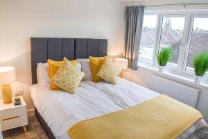 a bedroom with a bed with yellow pillows and a window at Anstey Heights Apartments in Bristol