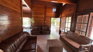 ein Wohnzimmer mit Ledermöbeln und Holzwänden in der Unterkunft Casa de Praia 3 Quartos Mussulo in Luanda