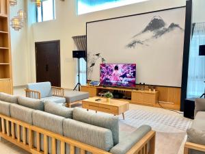 una sala de estar con sofás y una pantalla grande en Cheekaaboo Playhouse Ipoh, en Ipoh