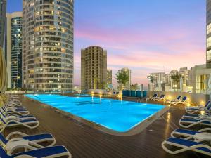 a swimming pool on the roof of a building with lounge chairs at Luxury Radiant Boulevard Residence in Mushayrib