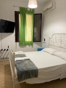 a bedroom with a white bed with a green curtain at Manu's House B&B in Porto Empedocle +15 photos