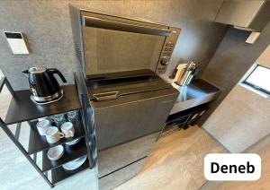 a small kitchen with a microwave and coffee cups at Room 2type Fuji Trip House Sepia 3F and Deneb 4F in Azagawa