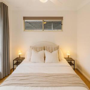 a bedroom with a large white bed with two lamps at Sunnybank Hills Haven - Family Comfort Retreat in Brisbane