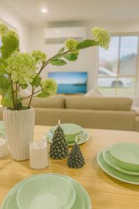 a table with green plates and a vase with flowers at Sunnybank Hills Haven - Family Comfort Retreat in Brisbane +10 photos