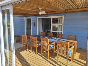 a porch with a table and chairs on a deck at The Mermaid's Tail in Pringle Bay