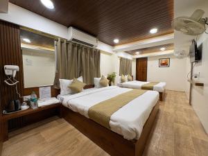 a hotel room with two beds and a television at Hotel Anantshree Inn Shree Mahakaleshwar Temple Ujjain in Ujjain