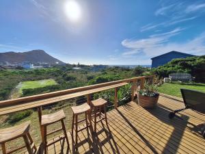 a deck with three chairs and a table on it at The Mermaid's Tail in Pringle Bay