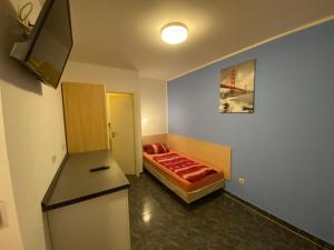 a small room with a bed and a refrigerator at Mayer-Pension in Ludwigshafen am Rhein