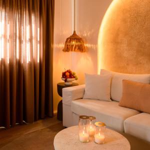a living room with a white couch and candles on a table at Themis Coddess Cave Suites in Santorini +23 photos